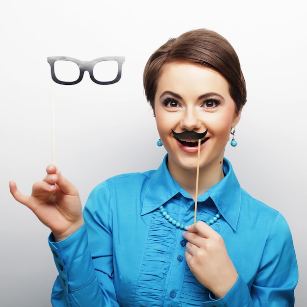 Young woman holding mustache and glasses 