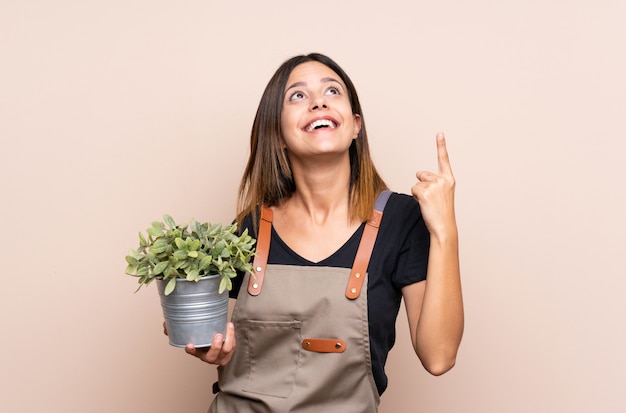 Young woman holding a plant intending to realizes the solution while lifting a finger up