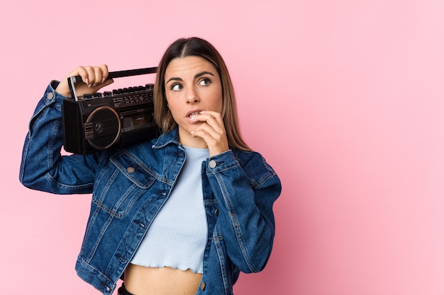 Young woman holding a radiocassette, relaxed thinking about something