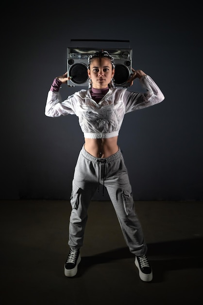 Young woman holding a retro tape recorder behind her head while looking at camera