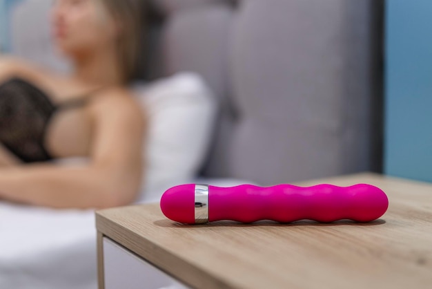 Young woman holding sex toy dildo vibrator in bed