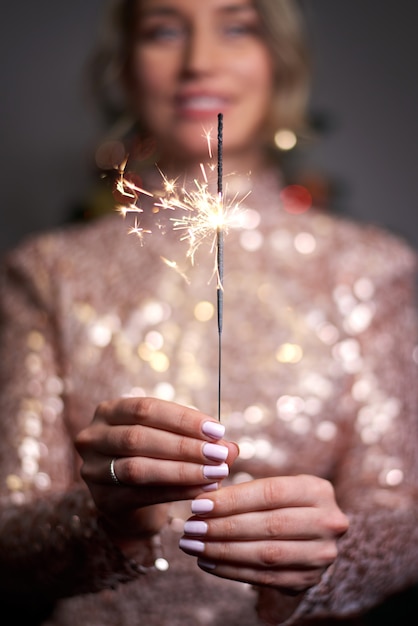 Young woman holding sparkler and smiling