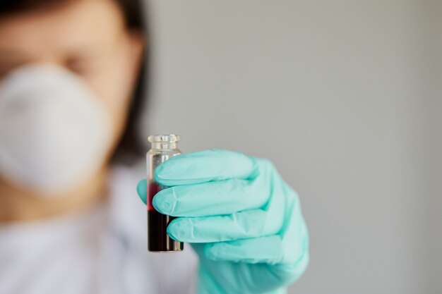 Young woman holding test tubes with blood and antidote in her hand.