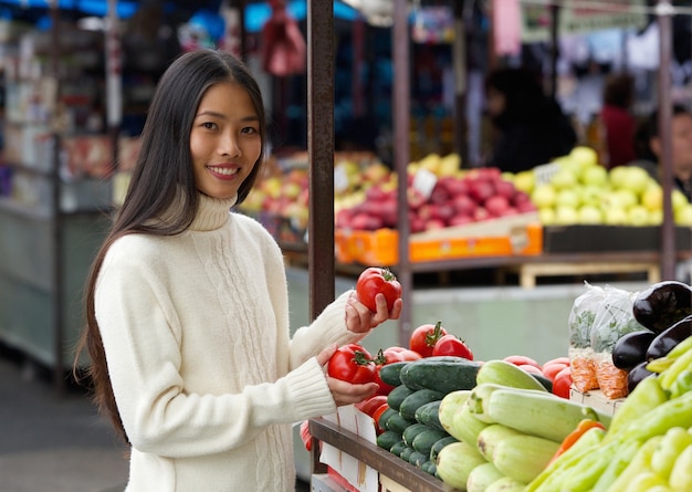 Young woman holding tomatoes at vegetable market