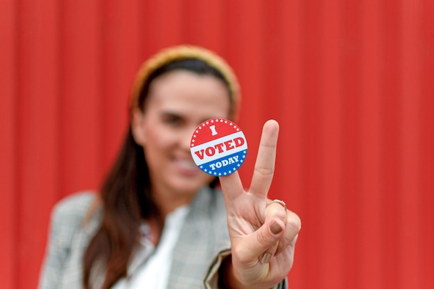 Young woman holding voting badge, sticker.