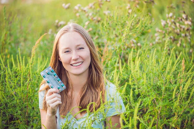 Young woman holds in her hand allergy tablets because of an allergy to ragweed