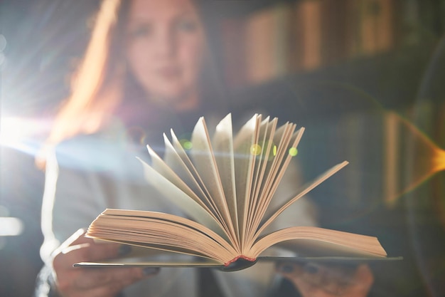 Young woman holds an open book. Small depth of field. Focus on the book.