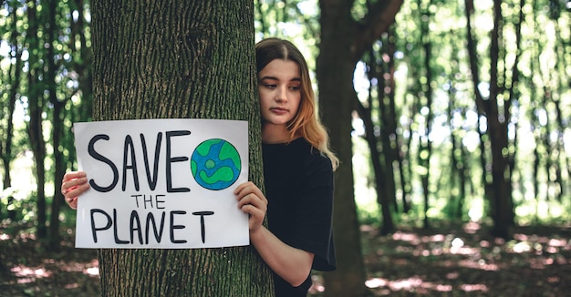 A young woman holds a poster with a call to save the planet