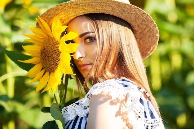 A young woman holds a sunflower in a blooming field of sunflowers