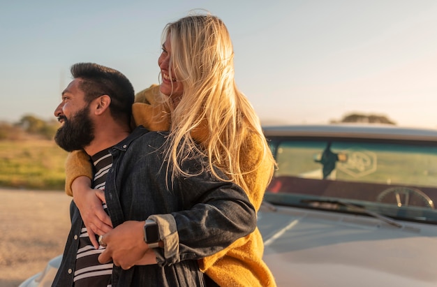 Young woman hugging her boyfriend from behind while staying on the car