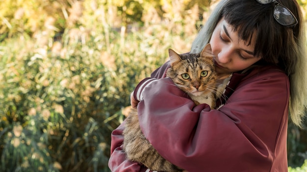 Young woman hugging her tabby cat in garden