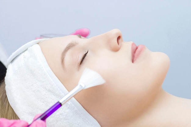 Young woman is applied with a brush to the mask on the face Procedure at the cosmetologist Relax