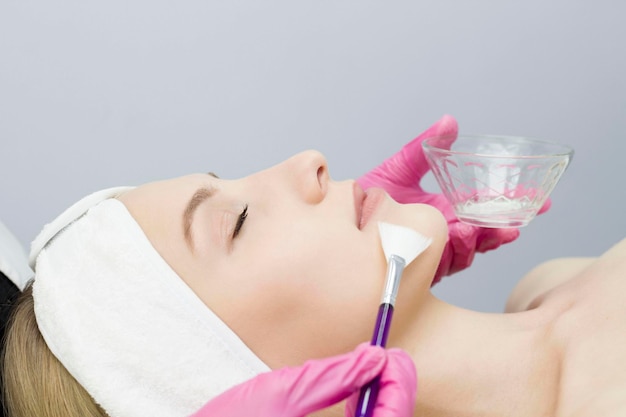 Young woman is applied with a brush to the mask on the face Procedure at the cosmetologist Relax