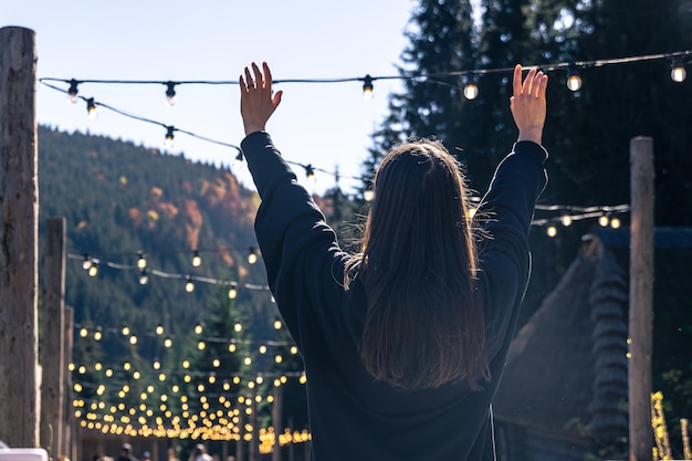 A young woman is dancing against the backdrop of mountains