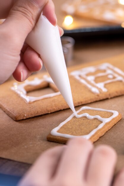 Young woman is decorating Christmas Gingerbread cookies