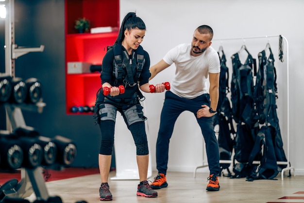 Young woman is doing EMS personal training with coach in the gym.