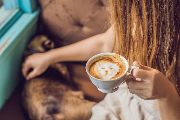 Young woman is drinking coffee and stroking the cat