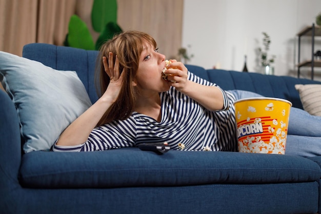 Young woman is focused on watching a movie eating popcorn