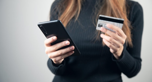 Young woman is holding credit card and smart phone