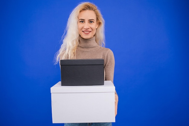 A young woman is holding a white and black box on a blue background