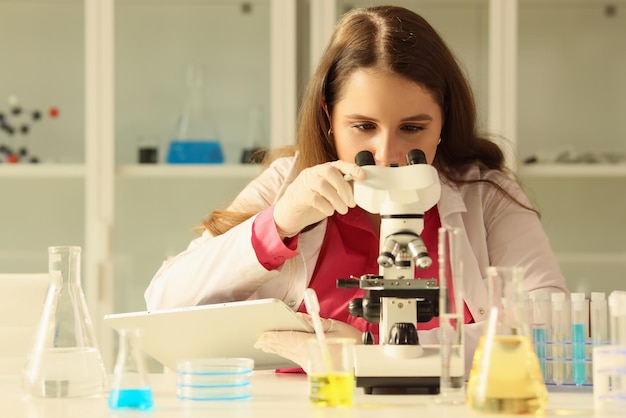 A young woman is looking at a microscope a closeup chemical fluid analysis fertilizer