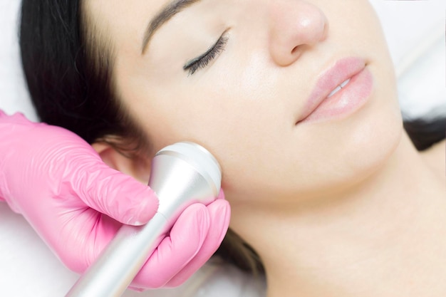 A young woman is lying on the RFlifting procedure for face skin tightening and face contour correction Closeup