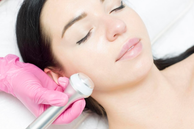 A young woman is lying on the RFlifting procedure for face skin tightening and face contour correction Closeup