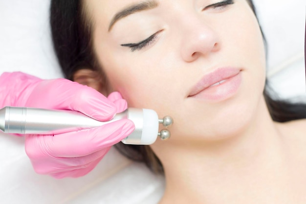 A young woman is lying on the RFlifting procedure for face skin tightening and face contour correction Closeup