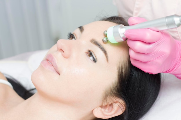 A young woman is lying on the RFlifting procedure for face skin tightening and face contour correction Closeup