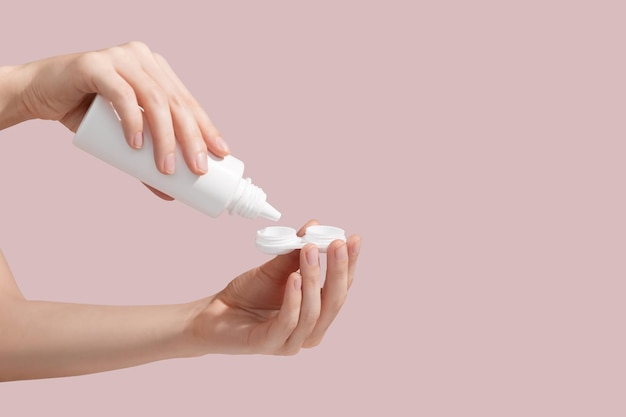 Young woman is pouring contact lens solution liquid for disinfecting and cleaning