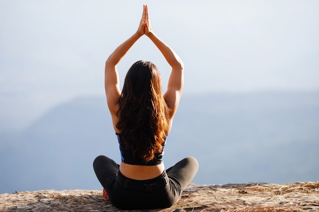 Young woman is practicing yoga at mountain in the summer