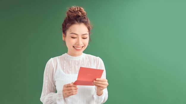 Young woman is reading Valentine card isolated over green