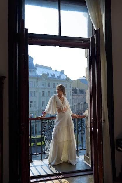 A young woman is resting on the balcony of her apartment overlooking the old town