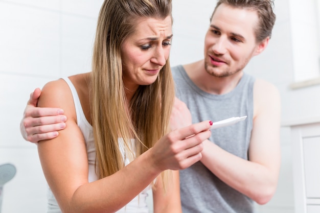 Young woman is sad about result of pregnancy test and her husban