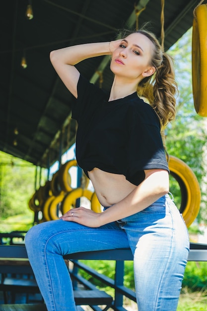 A young woman is sitting on a metal railing The girl is dressed in sportswear