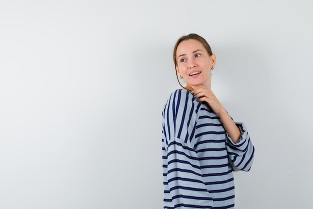 The young woman is smiling by holding her hand under chin on white background