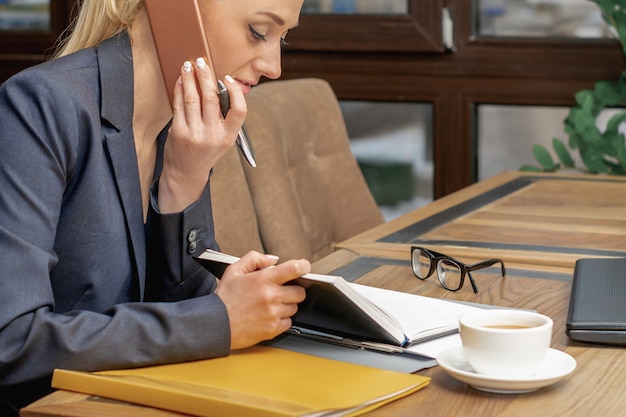 Young woman is talking by cell phone in office.