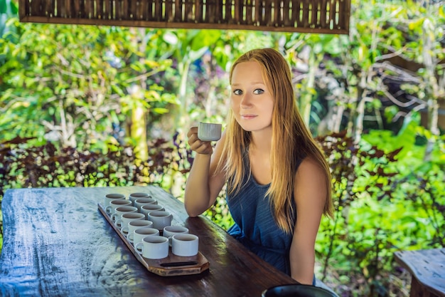 A young woman is tasting different kinds of coffee and tea, including coffee Luwak.