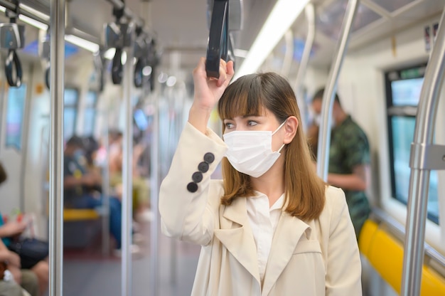 A young woman is wearing protective mask in metro , covid-19 protection , safety travel , new normal , social distancing , safety transportation , travel under pandemic concept