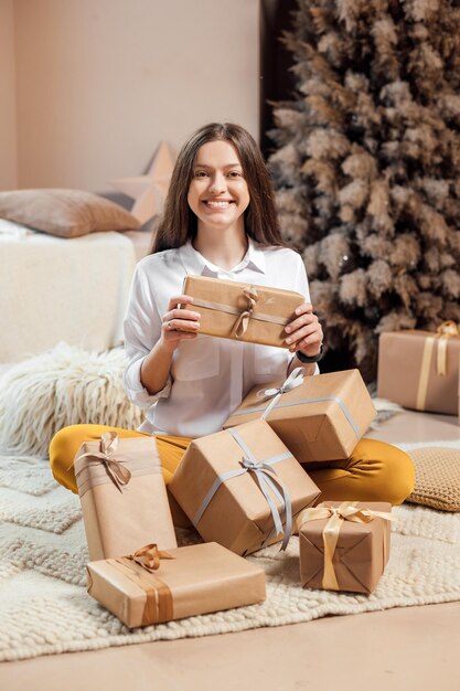 Young woman is wrapping christmas presents for holidays