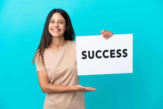 Young woman over isolated background holding a placard with text SUCCESS with happy expression