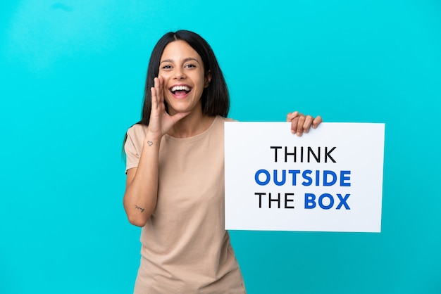 Young woman over isolated background holding a placard with text Think Outside The Box and shouting