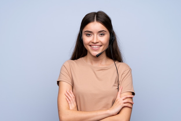 Young woman over isolated blue working with headset