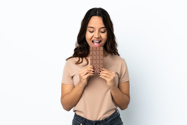 Young woman isolated eating a chocolate tablet