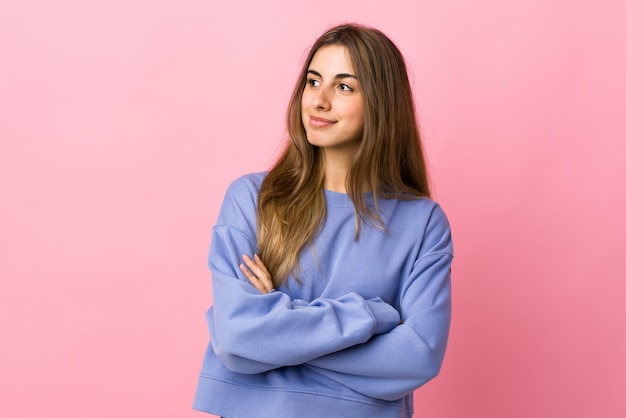 Young woman over isolated pink background looking to the side