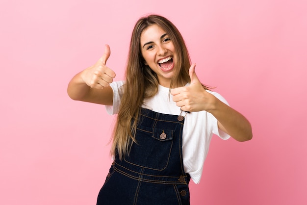 Young woman on isolated pink giving a thumbs up gesture