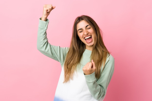 Young woman over isolated pink wall celebrating a victory