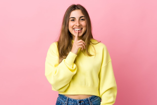 Young woman over isolated pink wall showing a sign of silence gesture putting finger in mouth