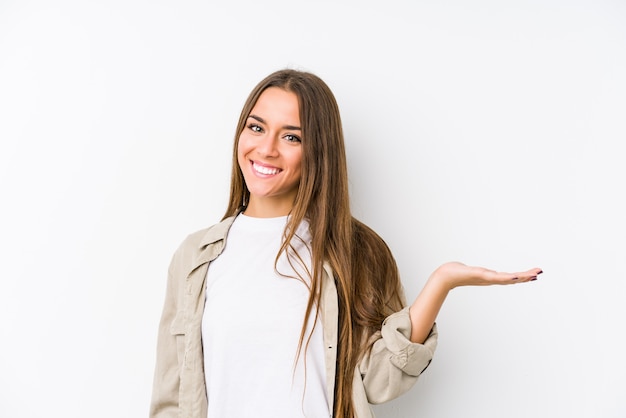 Young woman  isolated showing a copy space on a palm and holding another hand on waist