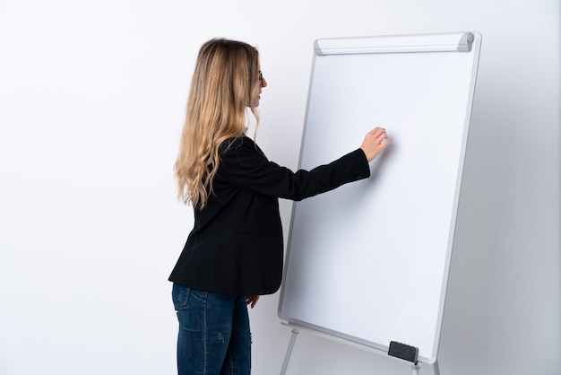 Young woman over isolated white wall giving a presentation on white board